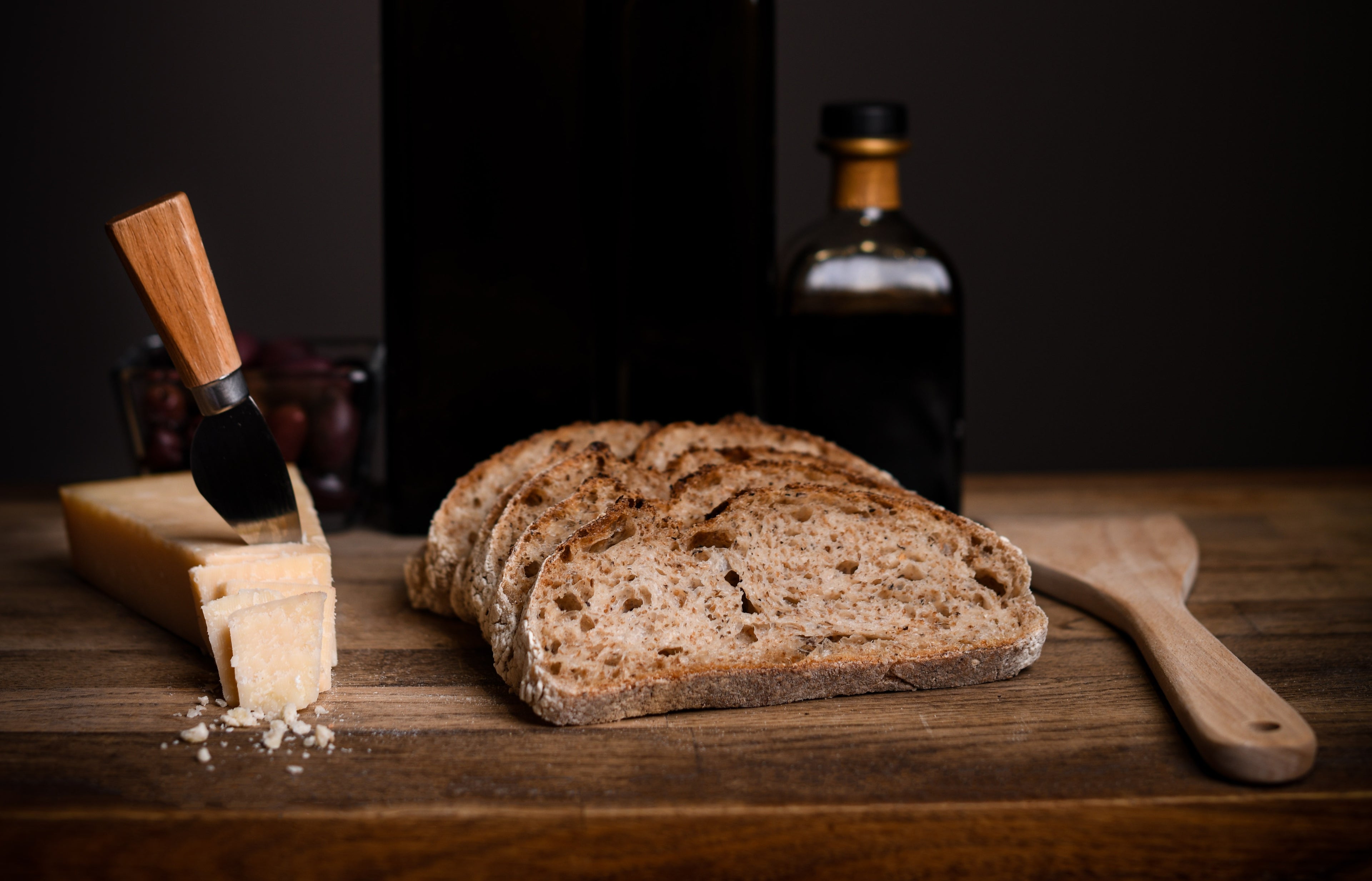 Pâine artizanală cu maia 100% naturală feliată, alături de parmezan maturat și ulei de măsline - Michael Artisan Bakery